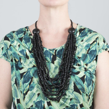 Black wooden bead necklace worn over a green print dress